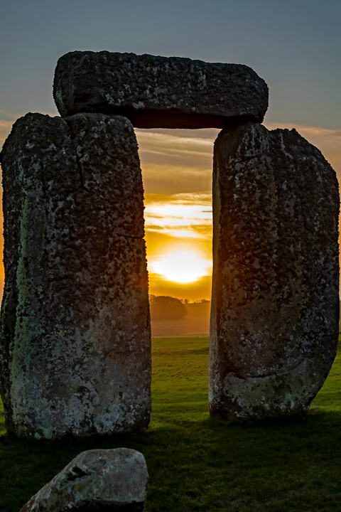 Picture of sunset/sunrise seen through two of the upright stones at Stonehenge. Photo by Hulki Okan Tabak on Unsplash, used by permission 